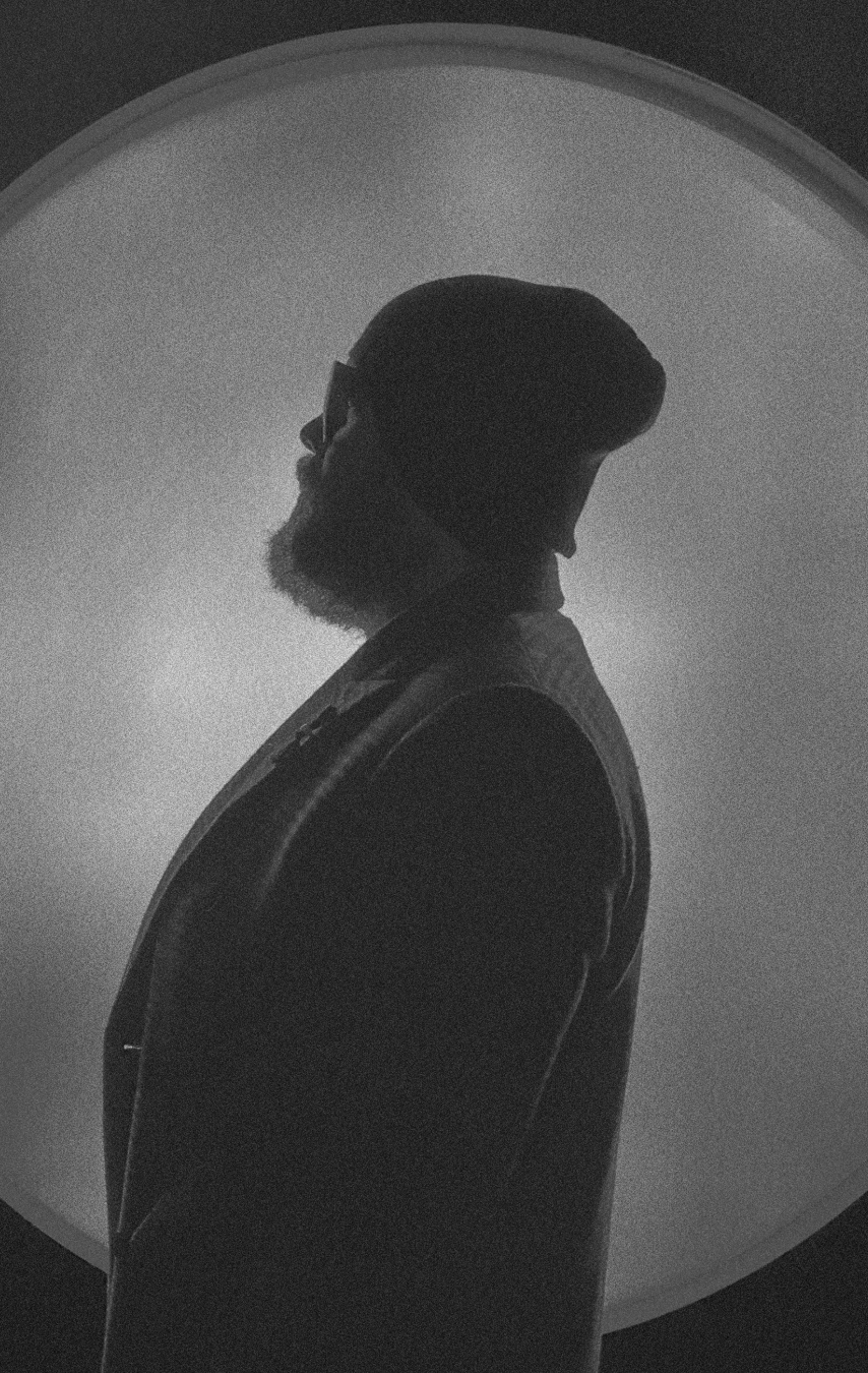 Diego Beas in profile, backlit silhouette inside a dark arch